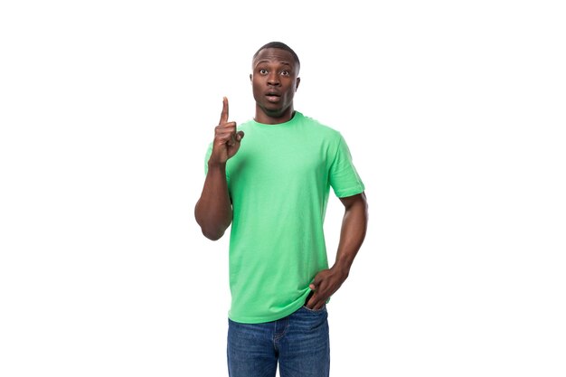 Un hombre americano de un año de edad, de inspiración positiva y guapo, vestido con una camiseta básica verde claro, señala con el dedo