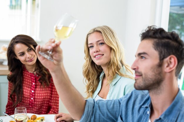 Hombre con amigos mirando el vaso de vino blanco