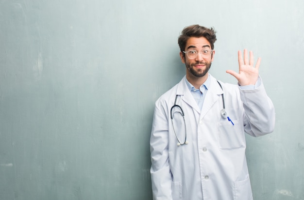 Hombre amistoso joven del doctor contra una pared del grunge con un espacio de la copia que muestra el número cinco