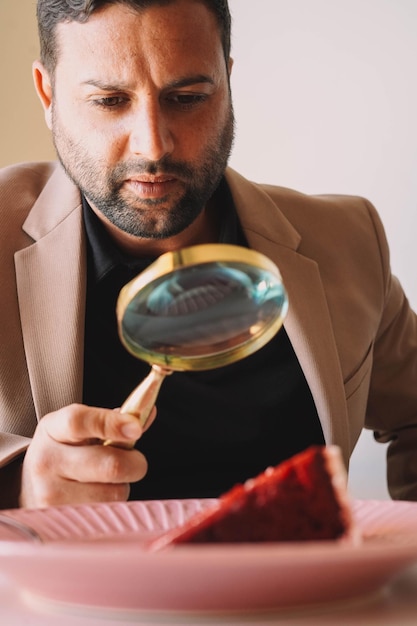 Hombre analizando un pastel de terciopelo rojo con una lupa