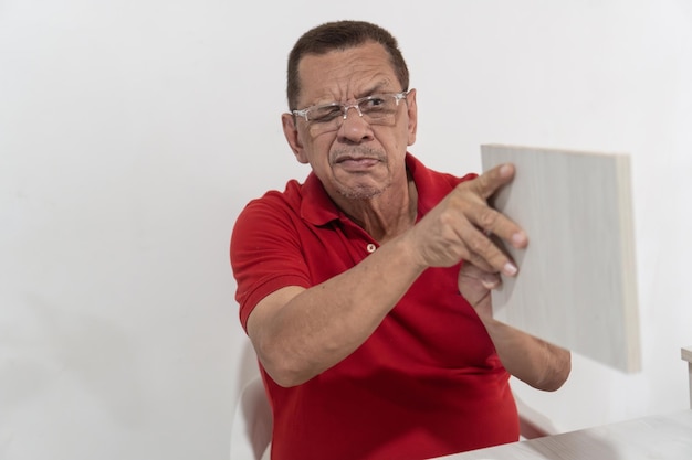 Hombre anciano inspeccionando una parte de un mueble de madera