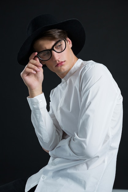 Hombre andrógino con sombrero posando con gafas