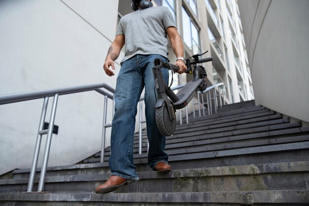 Hombre de ángulo bajo con scooter eléctrico