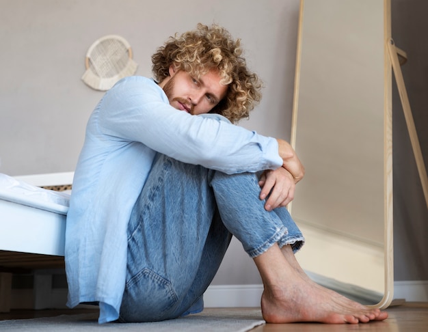 Foto hombre ansioso de tiro completo sentado en el piso