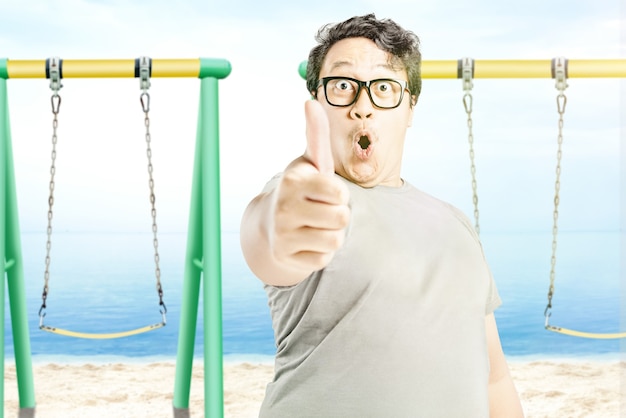 Hombre de anteojos mostrando el pulgar hacia arriba en la playa