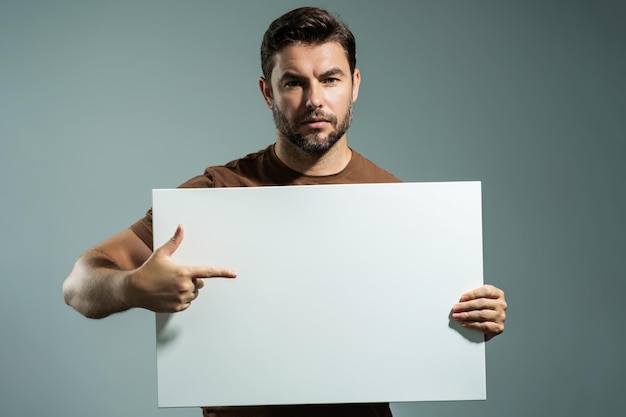 Hombre con anuncio de banner en blanco aislado en el fondo del estudio hombre sosteniendo cartel en blanco vacío que muestra en blanco