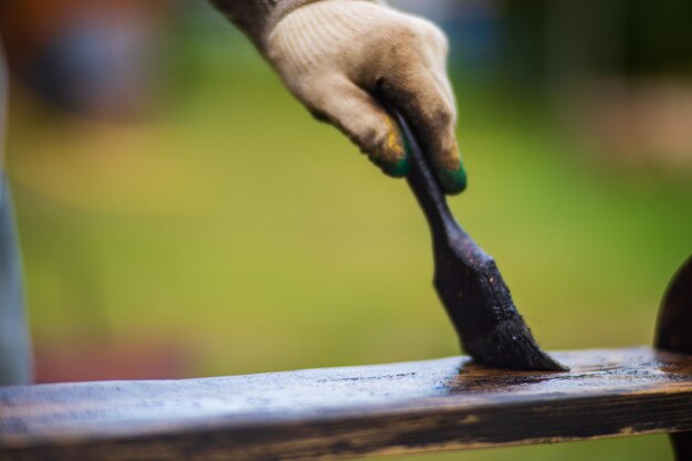 Un hombre aplica pintura a una superficie de madera con un trabajo de laca de pincel