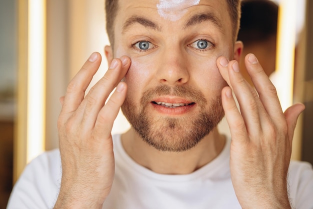 Foto hombre aplicando crema facial en casa