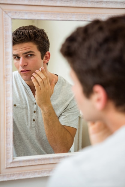 Hombre aplicando crema hidratante en la cara