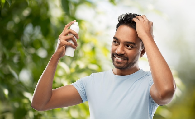 hombre aplicando spray para el cabello sobre un fondo natural