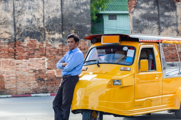 Hombre apoyado contra un Tuk Tuk