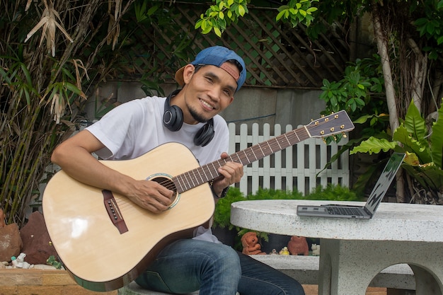 Hombre aprendiendo a tocar la guitarra en línea en casa