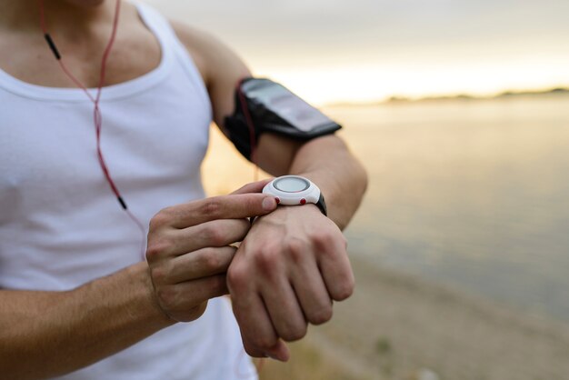 Hombre de la aptitud que usa un reloj elegante en parque