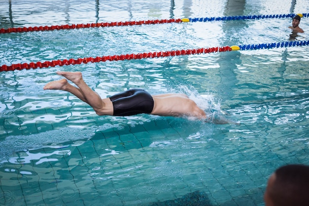 Hombre apto buceando en el agua en la piscina