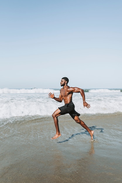 Hombre apto corriendo en la playa