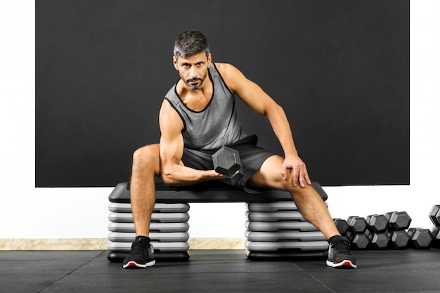 Hombre apto haciendo rizos con pesas en un gimnasio