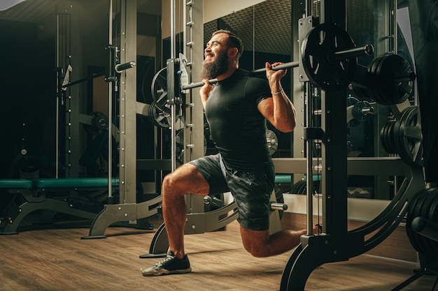 Hombre apto haciendo sentadillas en una máquina de entrenamiento