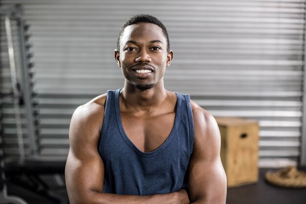 Hombre apto sonriente que presenta en el gimnasio del crossfit