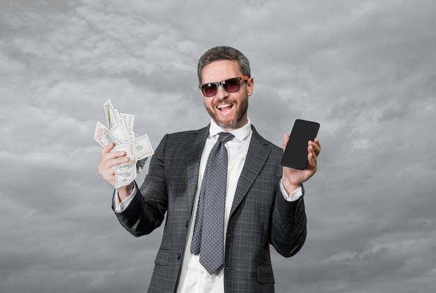 Hombre de apuestas alegre con dinero de la lotería hombre de apuestas al aire libre con dinero de lotería sostén foto de teléfono del hombre de apuesta con dinero de las loterías hombre de las apuestas con dinero de los loterías en el fondo del cielo