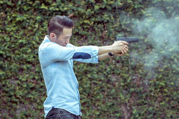 Hombre apuntando con una pistola mientras está de pie al aire libre