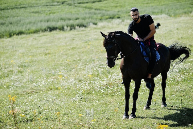 El hombre árabe de barba alta usa un caballo árabe negro.