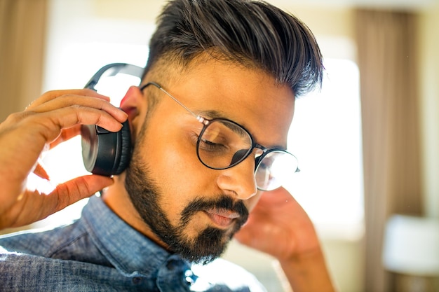 Hombre árabe barbudo escuchando meditación de audio capacitación empresarial crecimiento personal en un nuevo apartamento