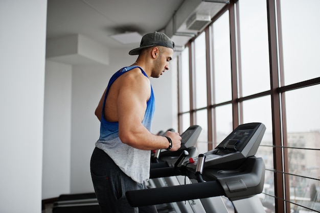 Hombre árabe en forma y musculoso corriendo en cinta de correr en el gimnasio