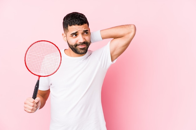 El hombre árabe joven que jugaba a bádminton aisló tocar la parte posterior de la cabeza, pensando y tomando una decisión.