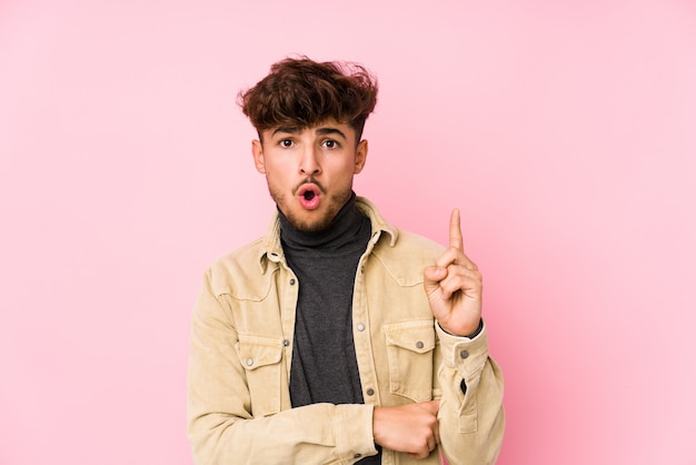 Hombre árabe joven que presenta en una pared aislada teniendo una gran idea, concepto de creatividad.