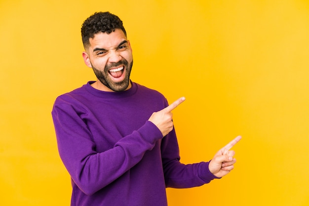 El hombre árabe joven de la raza mixta aisló señalar con los dedos a un espacio de la copia, expresando la emoción y el deseo.