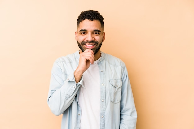 El hombre árabe joven de la raza mixta aisló la sonrisa feliz y confiada, tocando la barbilla con la mano.