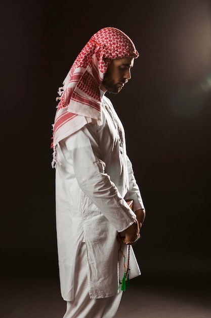 Hombre árabe con kandora de pie y rezando
