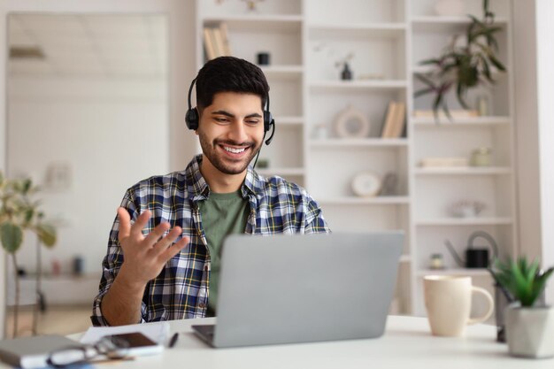 Hombre árabe que tiene una videollamada usando una computadora portátil y hablando