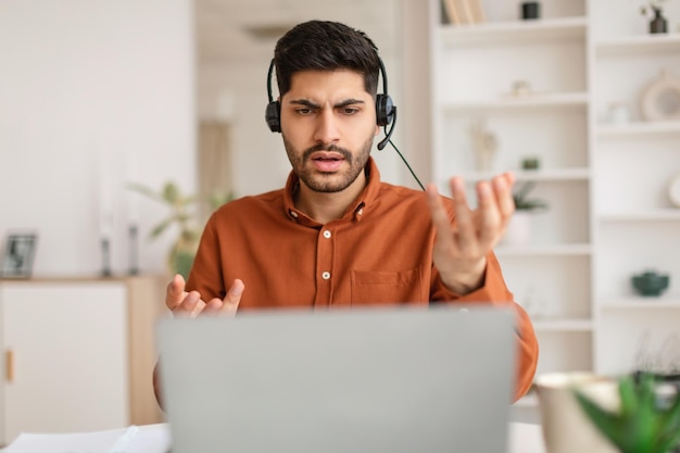 Hombre árabe que tiene una videollamada usando una computadora portátil y hablando