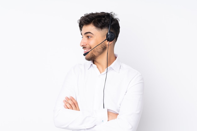 Hombre árabe telemarketer que trabaja con un auricular aislado en blanco mirando hacia el lado