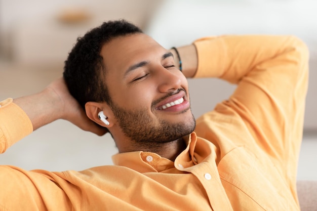 Hombre árabe tranquilo descansando en casa escuchando música