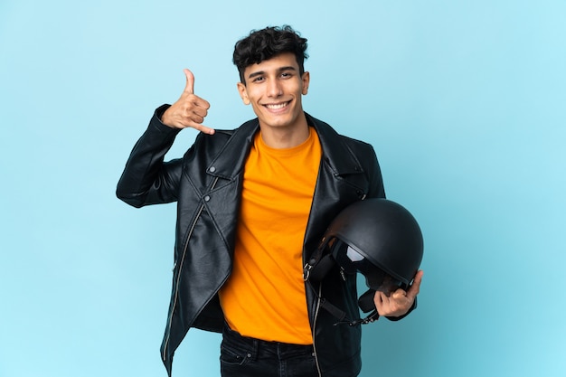 Hombre argentino con un casco de moto haciendo gesto de teléfono. Llámame señal