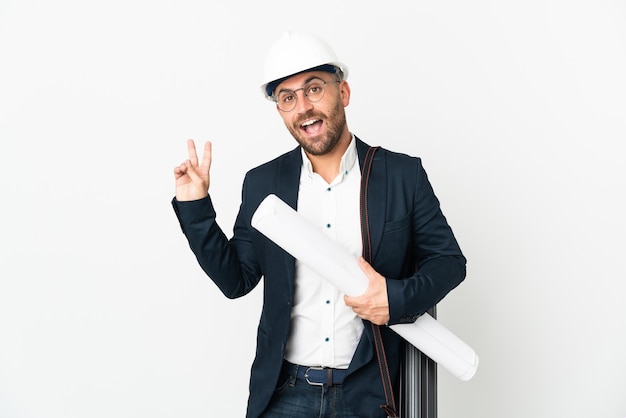 Hombre arquitecto con casco y sosteniendo planos aislados sobre fondo blanco sonriendo y mostrando el signo de la victoria