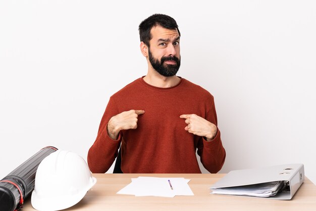 Foto hombre de arquitecto caucásico con barba en una mesa apuntando a sí mismo.