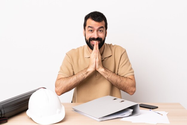 Hombre de arquitecto caucásico con barba en una mesa mantiene la palma junta