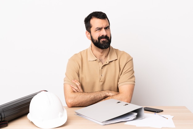 Hombre de arquitecto caucásico con barba en una mesa sintiéndose molesto.