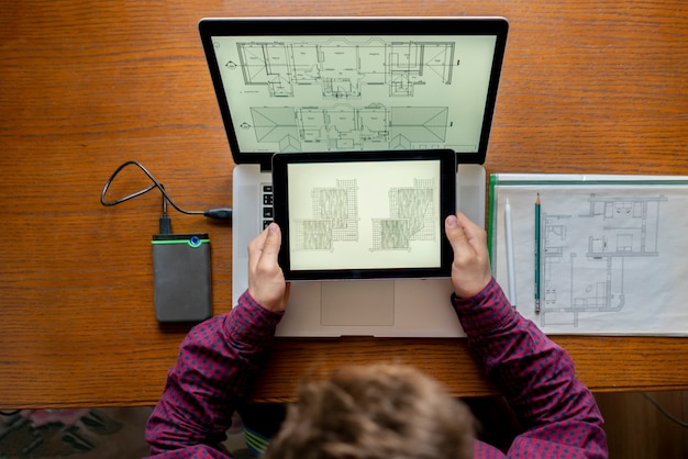 Hombre arquitecto trabajo con la computadora en la mesa de madera