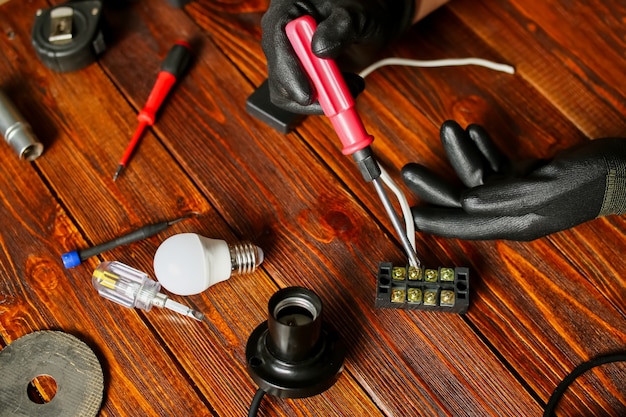 Un hombre arregla cables, una lámpara. Un electricista llamado hogar, destornilladores, bombillas, electrodomésticos y herramientas. Foto de alta calidad