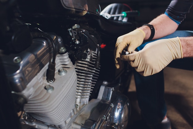 Hombre arreglando bicicleta. Hombre joven confidente que repara la motocicleta cerca de su garaje.