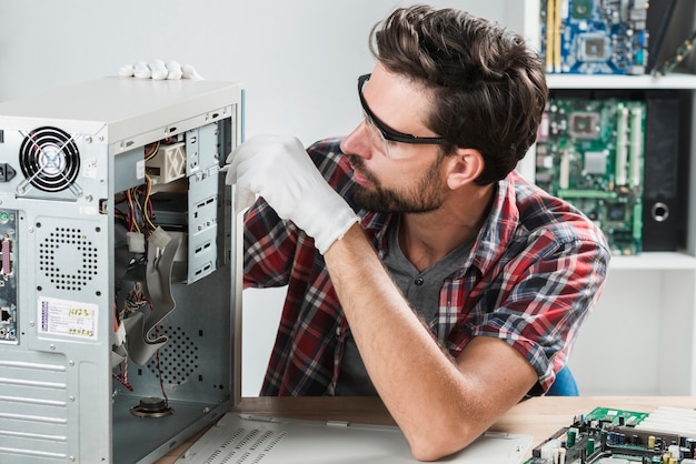 Hombre arreglando cpu con destornillador en taller