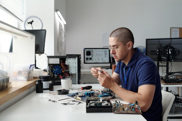 Hombre arreglando un dispositivo electrónico en el escritorio de la mesa de trabajo
