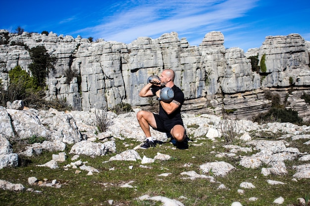 Hombre arrodillado con dos kettlebells