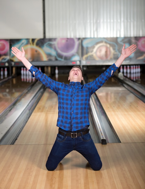 El hombre se arrodilló en bolos después de ganar.