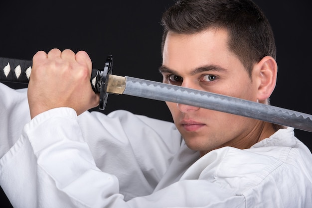 Un hombre de artes marciales en kimono con una espada.