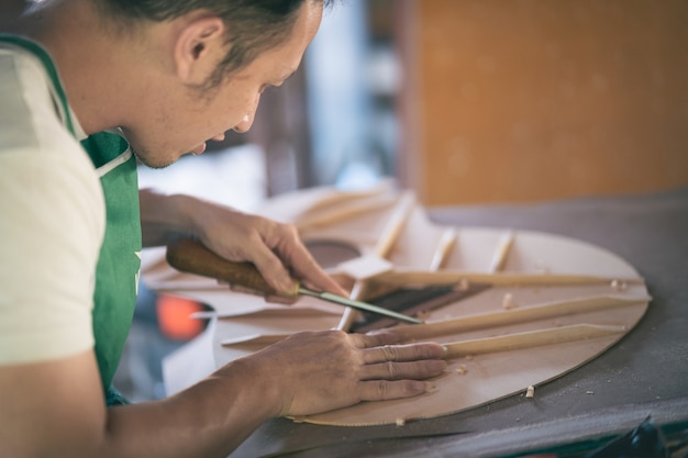 Hombre de artesanía haciendo guitarra en la mesa de madera, concepto de trabajo capenter